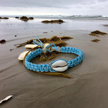Load image into Gallery viewer, Blue braided bracelet with a shell on a sandy beach