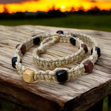 Load image into Gallery viewer, A thick flat hemp necklace with square wooden beads, displayed on a wooden surface with a sunset in the background.