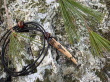 Load image into Gallery viewer, A handcrafted leather necklace with a large deer antler tip bone pendant featuring the Algiz rune, displayed on a rock with pine needles scattered around.