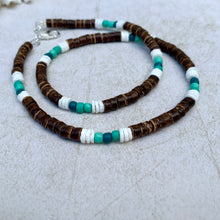 Load image into Gallery viewer, A handcrafted tribal necklace featuring natural litub shell and coconut beads in green and brown colors, with waxed coconut heishi beads and glass beads, displayed on a light background.