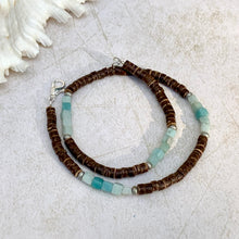 Load image into Gallery viewer, A handcrafted tribal-style necklace featuring natural coconut beads and amazonite beads in shades of blue and green, displayed on a textured background.