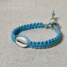 Load image into Gallery viewer, Blue braided bracelet with a shell on a textured beige background

