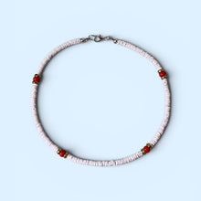 Load image into Gallery viewer, A delicate beaded necklace with small white disc beads and four red accent beads, displayed on a light blue background.
