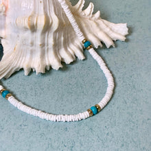 Load image into Gallery viewer, A white beaded necklace with small turquoise-blue and gold spacer beads, draped over a large white seashell on a light blue textured surface.
