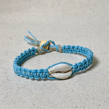 Load image into Gallery viewer, Blue braided bracelet with a cowrie shell on a light gray background

