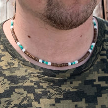 Load image into Gallery viewer, A person wearing a choker necklace with a combination of green and brown beads, including puka shell and coconut beads.
