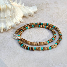 Load image into Gallery viewer, A handcrafted tribal necklace with natural coconut beads and blue glass beads, displayed on a beige background with a seashell and starfish.
