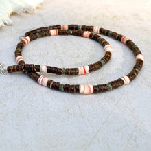 Load image into Gallery viewer, A handcrafted tribal necklace with red lip shell, coconut, and pyrite beads laid out on a light surface.
